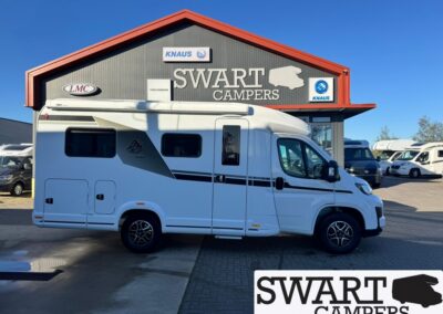White camper van parked in front of a Swart Campers dealership under a blue sky.