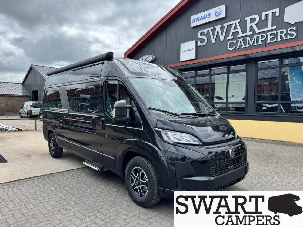 Black high-roof camper van parked outside Swart Campers showroom, signage visible above the building.