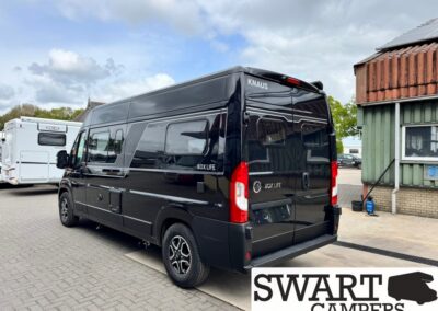 Rear and side view of a black Knaus Box Life camper van parked in a lot; Swart Campers branding visible in the corner overlay.