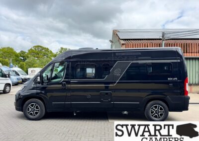 Side view of a black camper van with silver decals, parked in a lot.