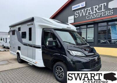 Motorhome with black and white cab parked outside a Swart Campers showroom; brand Knaus visible on the vehicle's front
