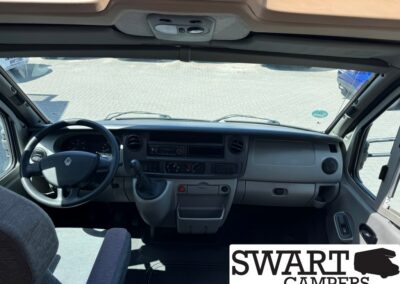 Interior view of a light-gray commercial vehicle cab: steering wheel, dashboard, gear shifter, and central controls visible from the driver's seat.