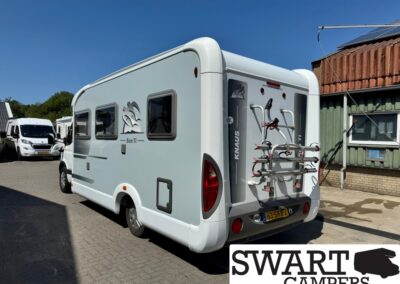 Rear view of a white motorhome with a bike rack mounted on the back, parked on a paved lot; SWART CAMPERS logo in the corner.