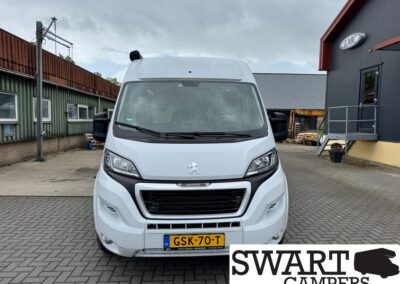 Front view of a white Peugeot camper van in an industrial yard, with a Dutch license plate GSK-70-T and SWART CAMPERS branding nearby.