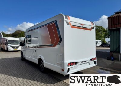 White motorhome parked in a lot, viewed from the rear-left, with bold orange and blue graphic stripes on the side.