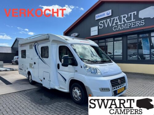 White motorhome parked in front of a Swart Campers shop; large red 'VERKOCHT' sign indicates it is sold.