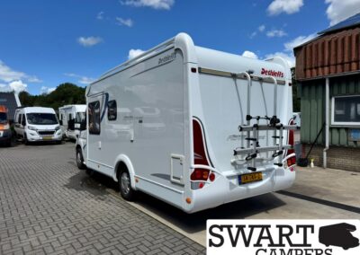 White Dethleffs motorhome with a rear bicycle rack parked on a paved lot, other campers nearby and a bright blue sky behind.
