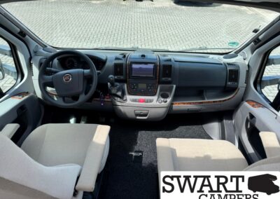 Cabin of a gray Fiat camper van, view from the passenger seat showing the steering wheel, center touchscreen, and gear shifter.