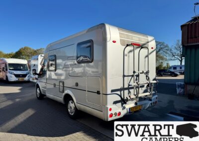 Rear view of a silver motorhome with a bike rack mounted on the back, parked among other campers; SWART CAMPERS logo in corner.
