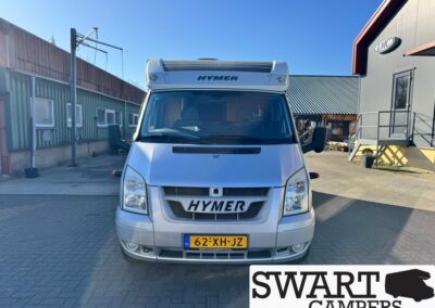 Front view of a silver Hymer camper van in a dealership yard, license plate 62-XH-JZ, Swart Campers logo bottom right.
