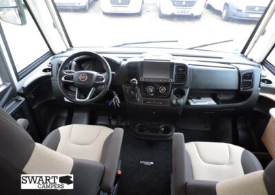Camper van dashboard with steering wheel on the left, large central touchscreen, climate controls, and two front seats; SWART CAMPERS logo bottom left.