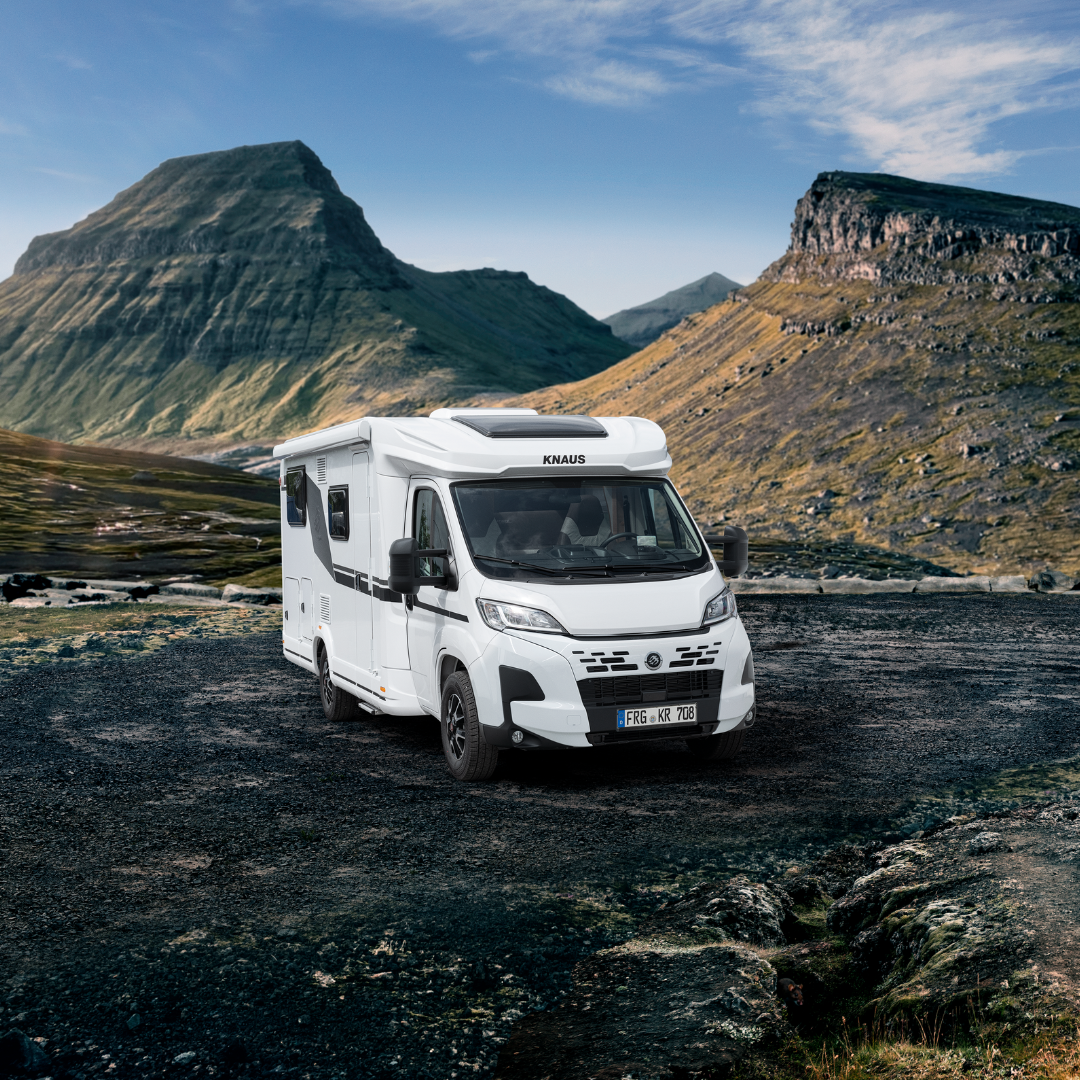 KNAUS LIVE TI - Swart Campers White camper van parked on a rocky gravel field with rugged mountains in the background under a blue sky, showing a remote landscape.
