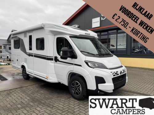 KNAUS LVE TI 650 MF PLATINUM SELECTION - Swart Campers White KNAUS camper van parked outside a dealership with a brown diagonal promo banner offering a weekly discount in Dutch. Shows Swart Campers branding on the banner and building window.