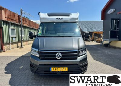 Front view of a dark gray VW camper van with a KNAUS rooftop, yellow Dutch license plate KFZ-89-Z, parked outdoors at a workshop yard.