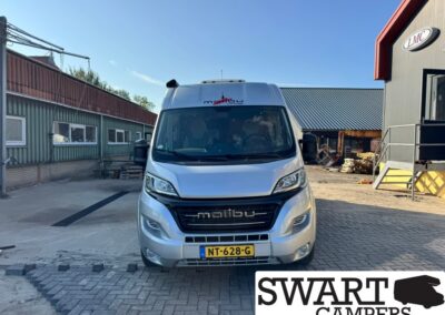 Front view of a silver Malibu motorhome van in an industrial yard, license plate NT-628-G, Swart Campers watermark in corner.