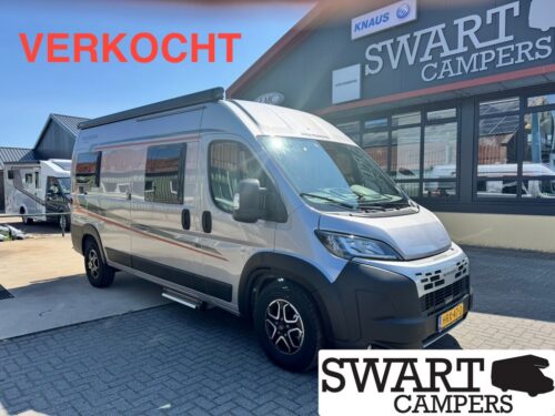 Sold camper van at a dealership, silver fiat-style van in foreground with 'VERKOCHT' in red text and 'SWART CAMPERS' signage in the background.