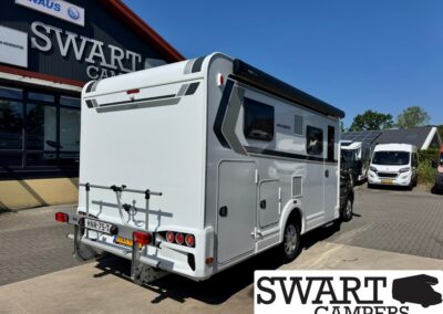 Rear view of a white motorhome with a bike rack on the back, parked at a Swart Campers dealership under a blue sky.