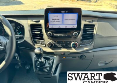 Interior of modern van dashboard with touchscreen infotainment displaying SkyRadio, climate controls below, and manual gear shift visible