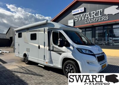 White camper van parked outside SWART CAMPERS showroom, dealership sign visible in the background