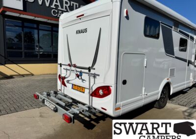 Rear view of a white KNAUS motorhome with a mounted bike rack on the rear bumper, parked in front of Swart Campers; Dutch license plate TT-573-H visible.