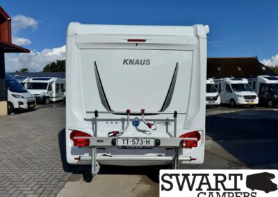 Rear view of a white KNAUS caravan with bike rack and red tail lights in a camper lot; license plate TT-573-H visible. SWART CAMPERS watermark bottom right.