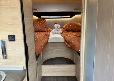 Cozy RV bedroom with two twin beds in brown polka-dot bedding and a teddy bear centered between them.