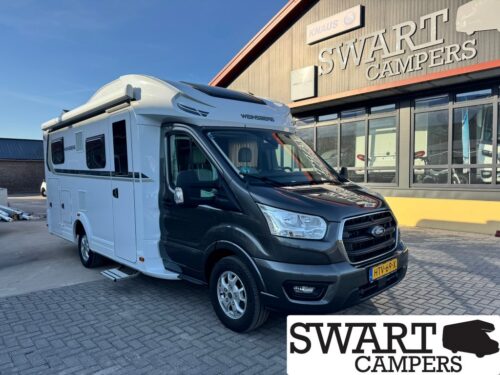 White and black motorhome parked outside a Swart Campers building with large logo sign in the background.