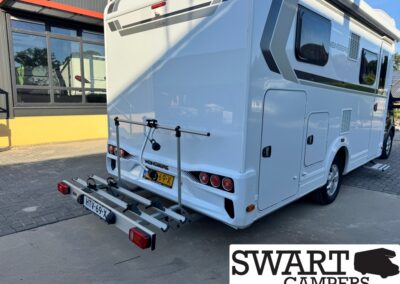 Rear view of a white motorhome with a bike rack attached to the back, Dutch license plate HTV-69-X, Swart Campers branding.