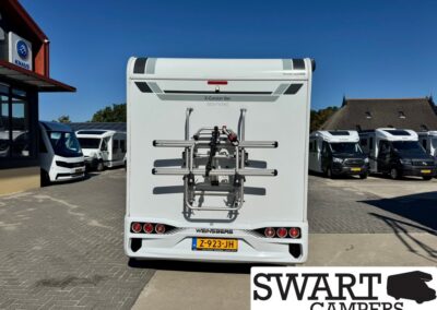 Rear view of a white Weinsberg caravan with a mounted bike rack, parked in a camper lot.