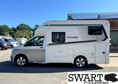 White Weinsberg motorhome, side view, parked on a paved lot with solar panels on the roof and a Swart Campers watermark bottom right.
