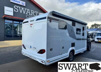 White KNAUS motorhome parked outside the Swart Campers dealership, with the large Swart Campers sign on the building visible behind it.