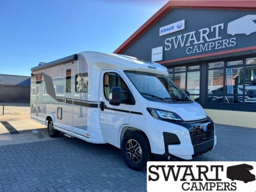 White Knaus motorhome parked outside Swart Campers showroom, with large SWART CAMPERS sign on the building.