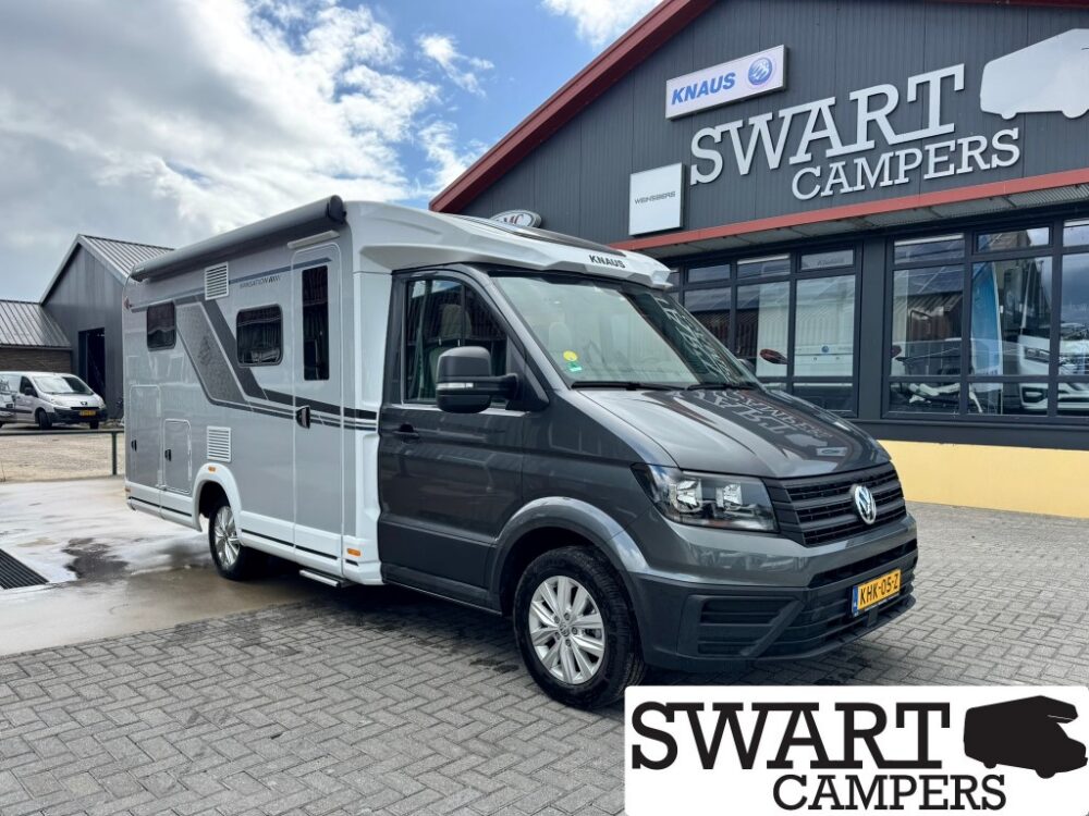 Grey and white Volkswagen camper van parked outside the Swart Campers showroom, with the building sign visible.