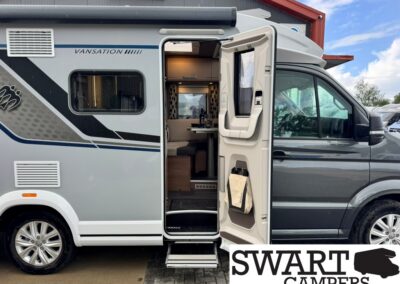 Gray camper van with side door open, revealing an interior dining area and seating; exterior features dark graphics and “SWART CAMPERS” branding nearby.