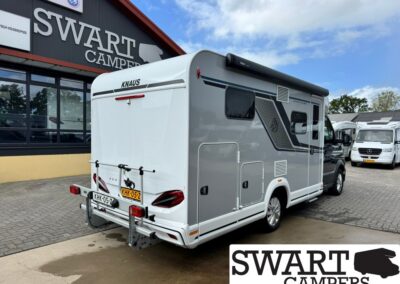 White Knaus motorhome parked outside Swart Campers with a rear bike rack visible at the back.