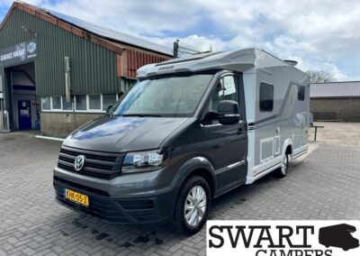 Grey Volkswagen camper van with a raised roof parked outside a workshop, Swart Campers logo visible in the foreground and on the building signage