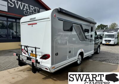 Rear and side view of a white Knaus motorhome with a bike rack on the back, parked at Swart Campers showroom.