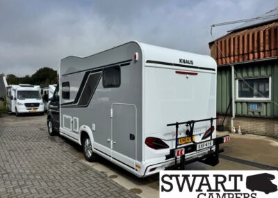 White KNAUS caravan with a rear bike rack parked on a paved lot, SWART CAMPERS logo visible in the corner.