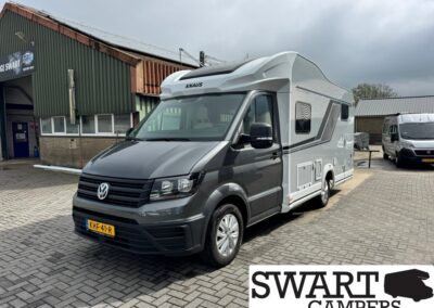 Front three-quarter view of a grey KNAUS camper van with raised roof, parked at a camper dealership lot.