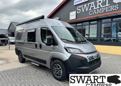 Silver high-roof camper van parked outside Swart Campers showroom.