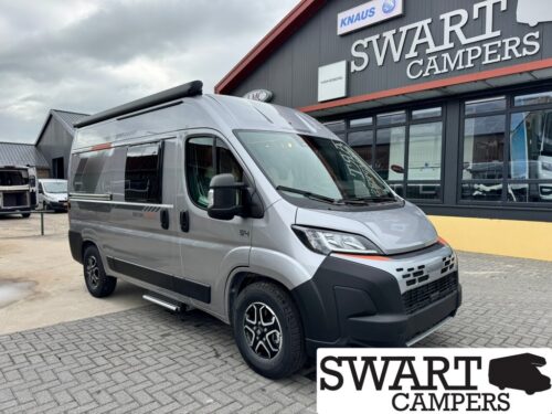 Silver high-roof camper van parked outside Swart Campers showroom.