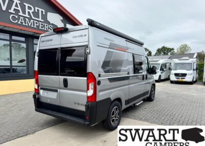 Rear-and-side view of a silver Weinsberg CoroBus camper van at a camper dealership, with SWART CAMPERS branding visible on the building and logo.