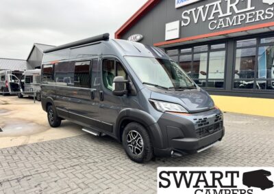 Dark gray camper van with raised roof parked in front of a Swart Campers shop storefront.