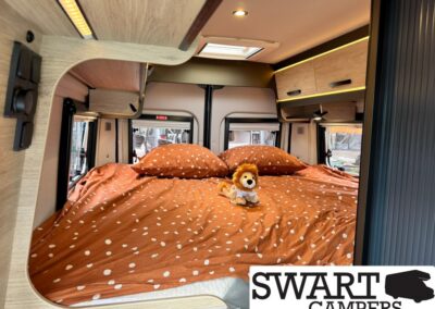 Camper van bedroom with an orange polka-dot bedspread and a small plush lion on the bed.