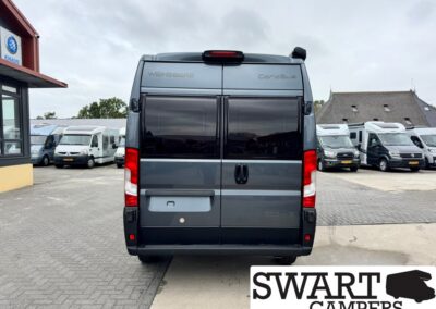 Rear view of a gray Wansberg CaraBus camper van in a dealership lot, showing rear doors, tinted windows, and red taillights with a Swart Campers logo overlay in the corner.