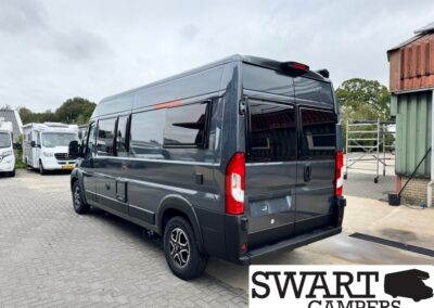 Dark gray high-roof camper van parked in a lot with other motorhomes, SWART CAMPERS logo visible in the corner