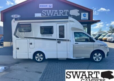 White camper van parked in front of a Swart Campers building with logos, side view showing windows and side door