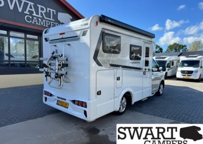Rear view of a white motorhome with a mounted bicycle rack, parked outside a camper dealership named Swart Campers.