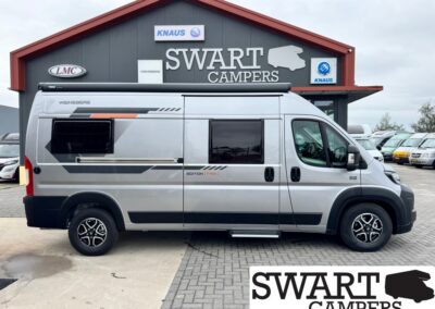 Silver camper van parked in front of a Swart Campers building, side view with windows and steps visible in the foreground.