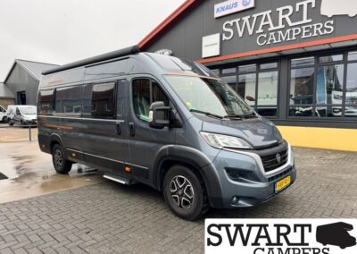Dark gray camper van parked in front of a Swart Campers storefront, side view with roof awning extended